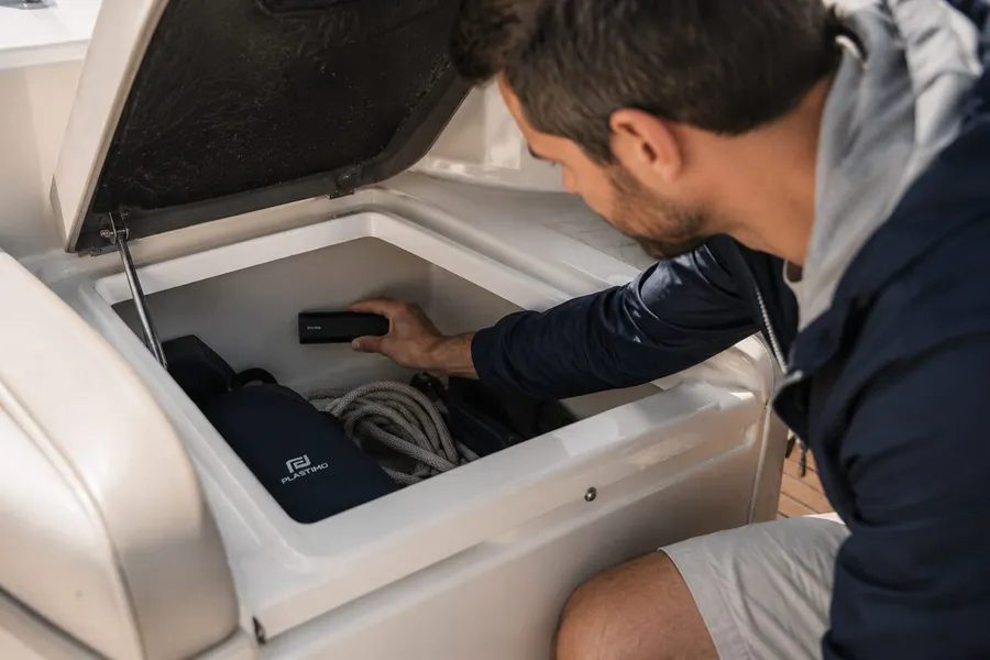 Man placing a GPS Tracker Pro Max inside a boat storage locker