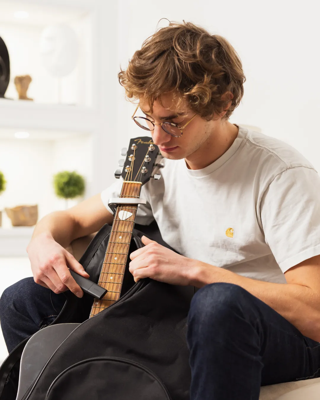 Ein junger Mann versteckt einen Tracker GPS Classic in einem Gitarrenkoffer