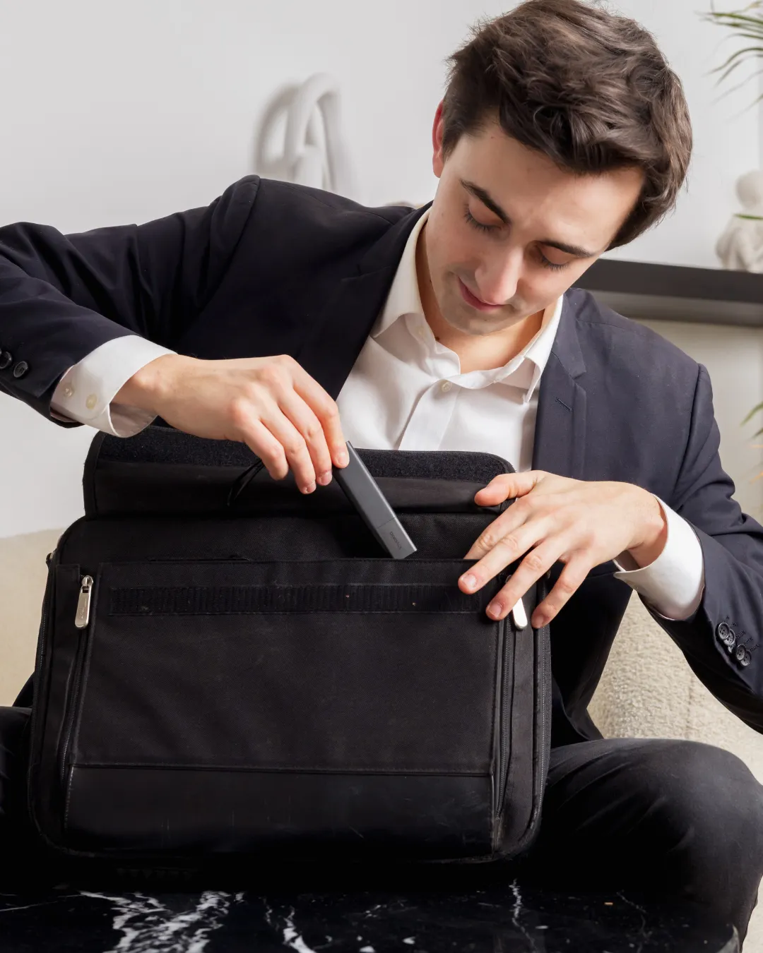 a man placing a GPS Pro Tracker into his laptop bag
