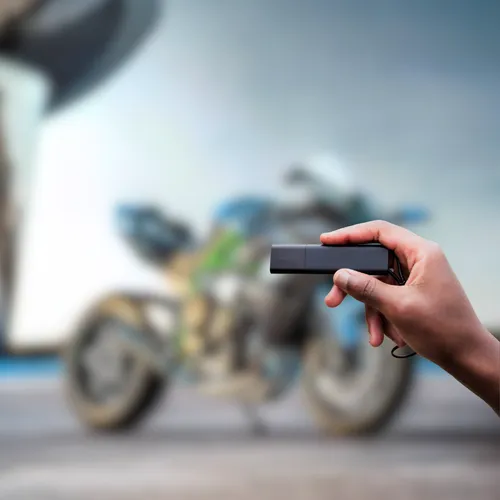 a person holding their Tracker GPS Pro in front of their motorcycle