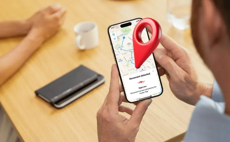 A man sitting at a table receives a movement alert notification on his Invoxia GPS app.