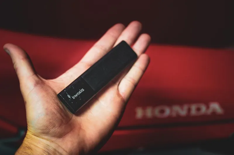 A Tracker GPS Classic in a hand with is a fancy red motorcycle in the background