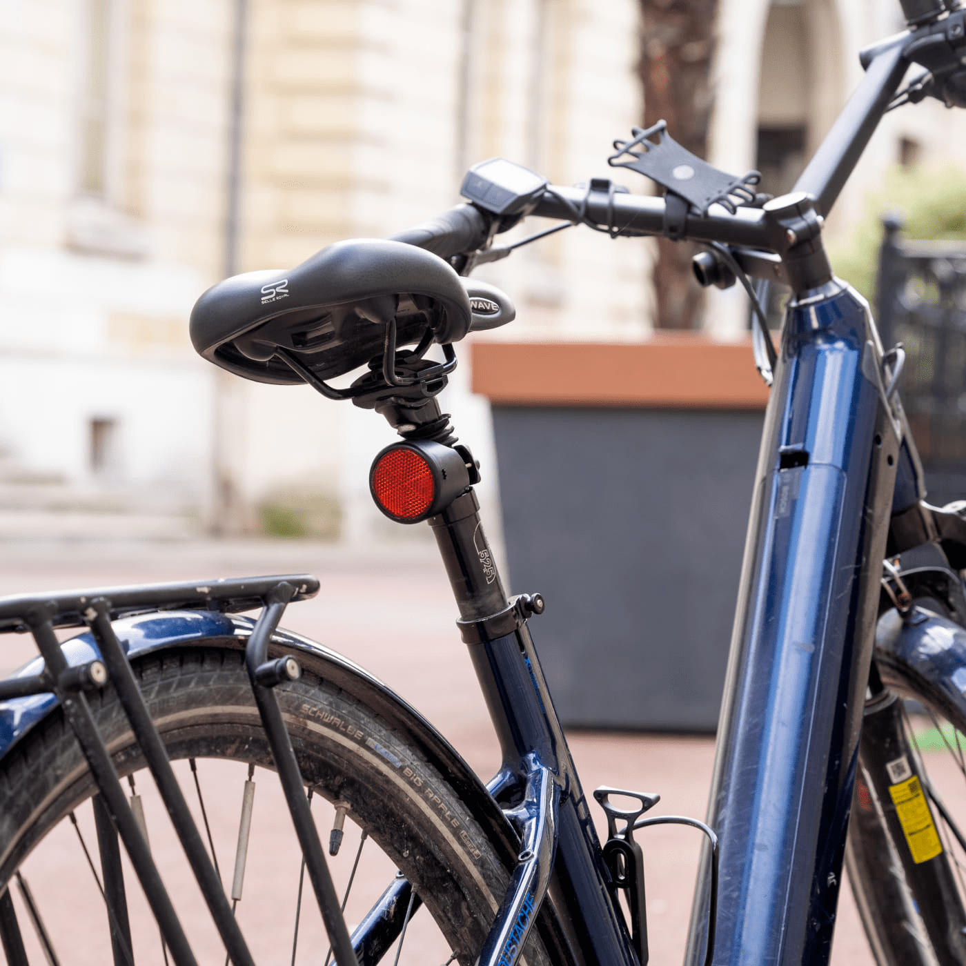 An Invoxia Bike Tracker attached to the seat post of a bike resting against a tree